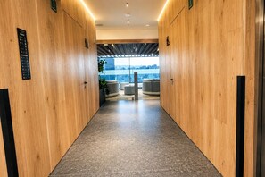 A hallway with wooden walls and a tiled floor leading to a seating area with a city view. - 24th-Floor Condo: City View, Pool, Heart of CDMX (Mexico City)
