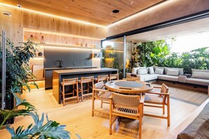 A modern kitchen with a central island, wooden flooring, and a dining area with a round table and chairs. - 24th-Floor Condo: City View, Pool, Heart of CDMX (Mexico City)