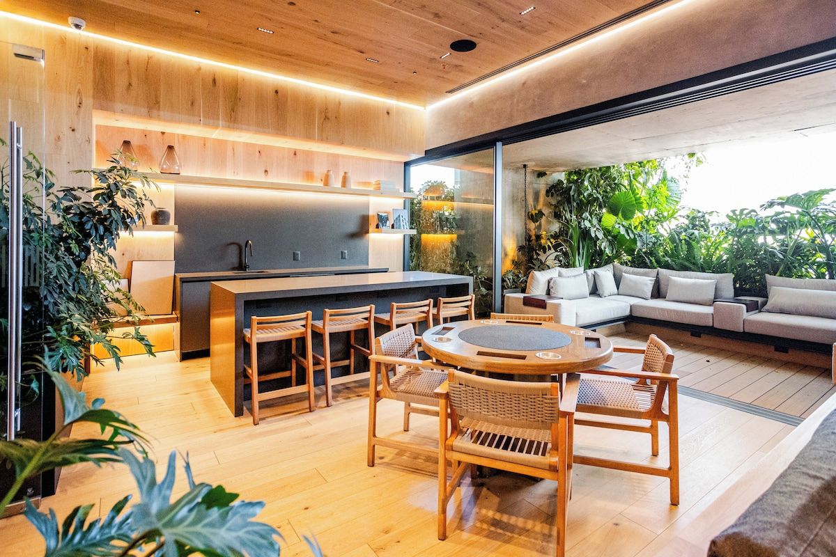 Een moderne keuken met een centraal eiland, houten vloeren en een eethoek met een ronde tafel en stoelen.