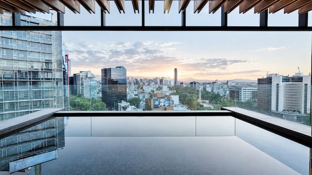 Interior moderno com uma grande janela com vista para a paisagem urbana ao pôr do sol.