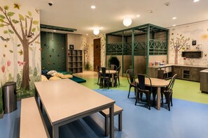 Ein Spielzimmer für Kinder mit Tisch, Stühlen, einem Bücherregal und einer Kletterwand.