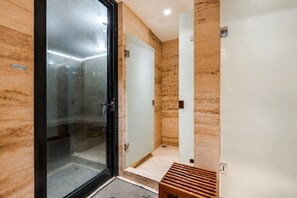 A modern bathroom with a glass shower enclosure, a wooden bench, and a marble wall. - Luxury 1BR Condo w/ Pool, Jacuzzi, Near Antara (Mexico City)