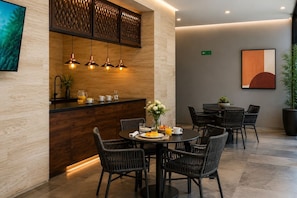 Een moderne eetruimte met een houten bar, een ronde tafel en rieten stoelen.