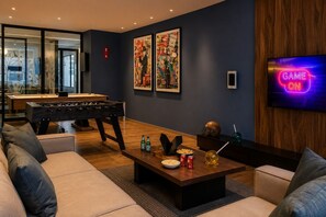 Ein modernes Wohnzimmer mit einem Kicker, einem Flachbildfernseher und Kunstwerken an der Wand.