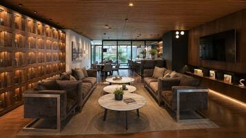 A modern interior with a wooden ceiling, a large TV, and a seating area with sofas and round tables.
