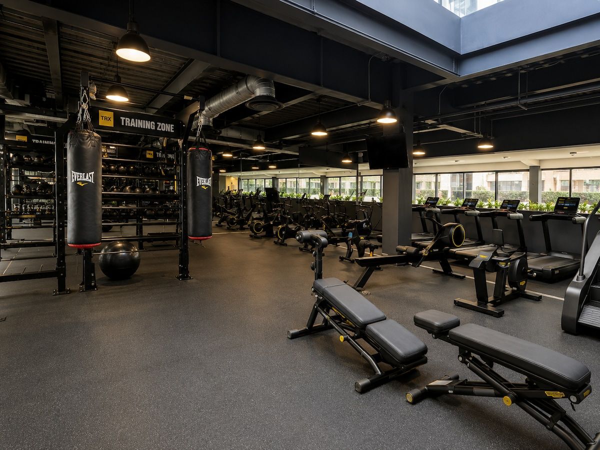 A gym with various exercise equipment, including treadmills and weight machines, in a spacious indoor area with large windows.