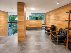 Ein modernes Interieur mit einer Holzwand, einem Empfangstresen und einer Sitzecke.