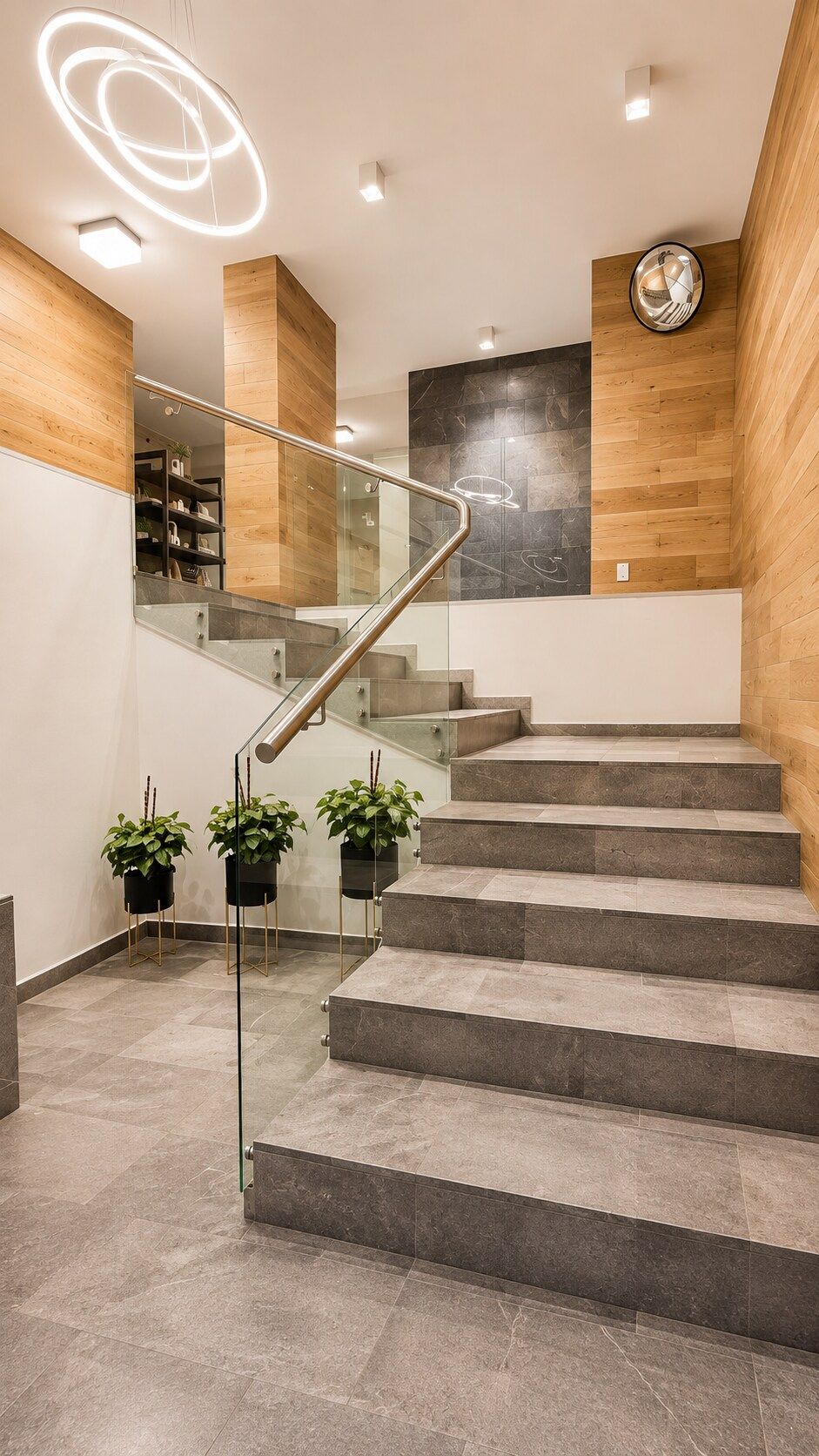 Eine moderne Treppe mit Glasgeländern und Pflanzkübeln.