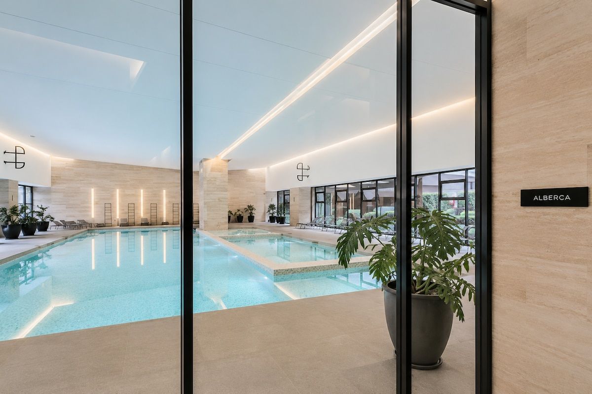 Une piscine intérieure avec des chaises longues et des plantes en pot, ainsi qu’un panneau indiquant l’emplacement.