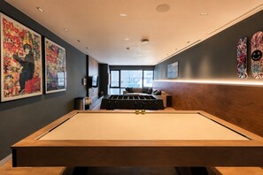 A pool table in a room with artwork on the walls, a sofa, and a window providing a view. - Polanco Condo: Heated Pool, Gym & Antara Access (Mexico City)