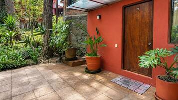 A red building with a wooden door, potted plants, and a tiled patio.