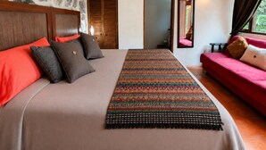Ein Schlafzimmer mit einem großen Bett, einem roten Sofa, einem gemusterten Teppich und einer Steinwand.