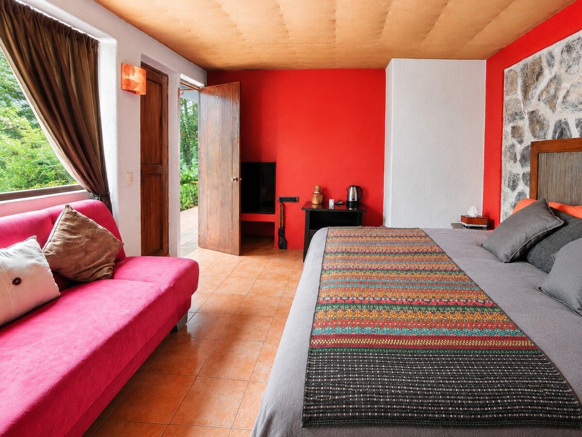 Ein Schlafzimmer mit einem Bett, einem Sofa, einem Fernseher und einem kleinen Tisch mit einem Wasserkocher.