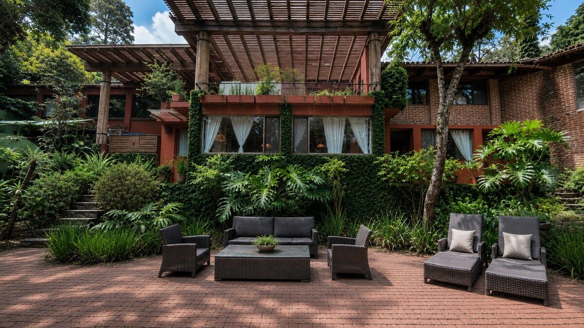 A patio with outdoor furniture, a pergola, and a brick building with windows.