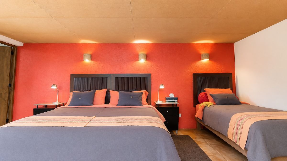 A hotel room with two beds, each with a headboard, bedside tables, and lamps.