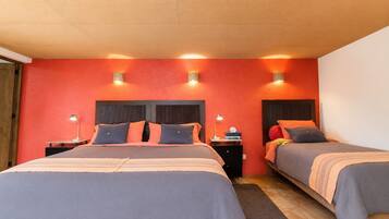 A hotel room with two beds, each with a headboard, bedside tables, and lamps.