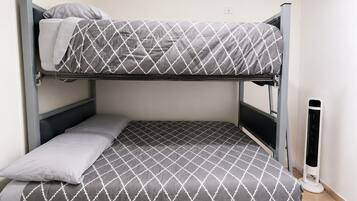 Uma cama beliche com colcha estampada, um travesseiro e um aquecedor portátil.
