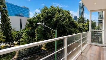 Uma varanda com vista para paisagem urbana, incluindo um edifício moderno e árvores.