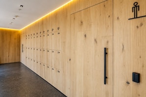 A row of wooden lockers with numbers indicating room assignments, a black handle on the right, and a small red light on the far right. - Luxury Loft w/ Rooftop Pool & City Views (Mexico City)