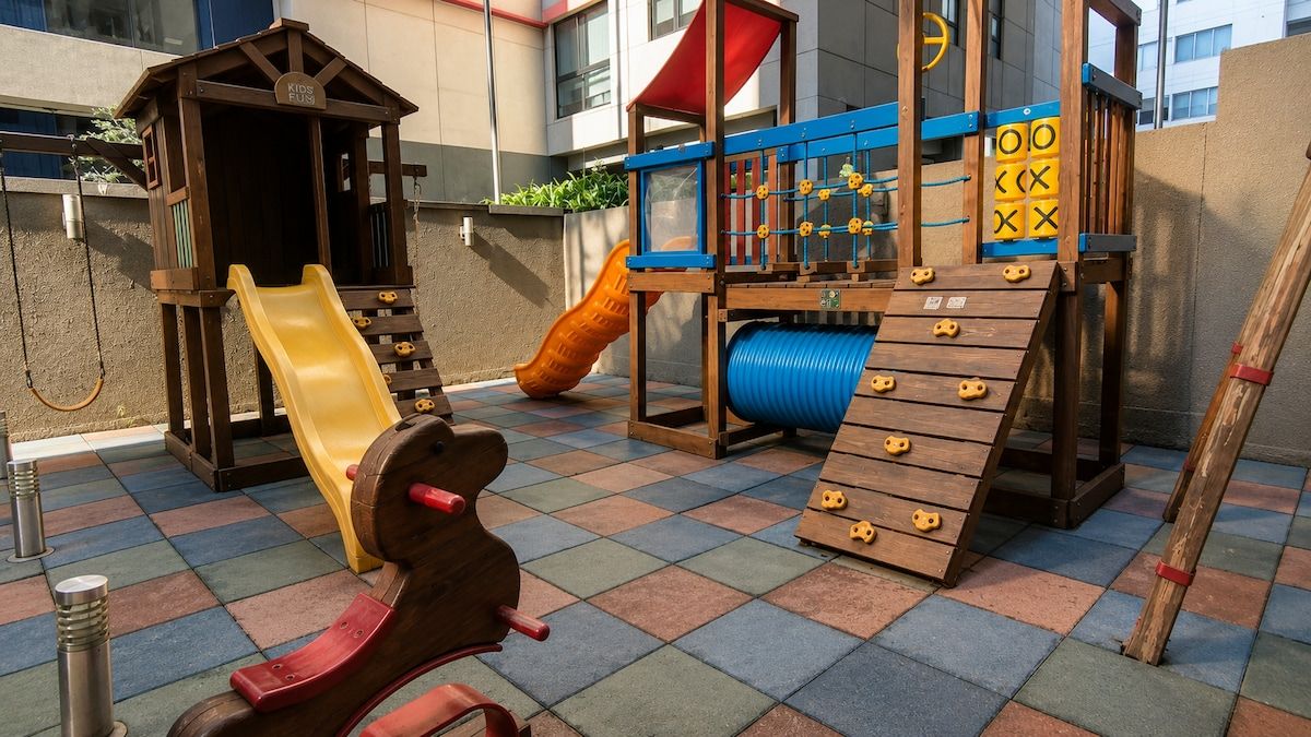 Een kinderspeelplaats met een glijbaan, een klimconstructie en een houten speelhuisje.