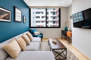 A modern living room with a sofa, a coffee table, and a TV mounted on the wall. - Polanco 20th-Floor Condo: Pool, Gym, City Views (Mexico City)