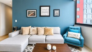 A living room with a sectional sofa, a blue armchair, and a coffee table with two white vases. - Polanco 20th-Floor Condo: Pool, Gym, City Views (Mexico City)