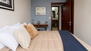 A bedroom with a bed, a desk, and a door leading to a bathroom. - Polanco 20th-Floor Condo: Pool, Gym, City Views (Mexico City)