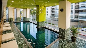A hotel pool with a clear view of the street outside, a clock on the wall, and a potted plant near the pool. - Polanco 20th-Floor Condo: Pool, Gym, City Views (Mexico City)
