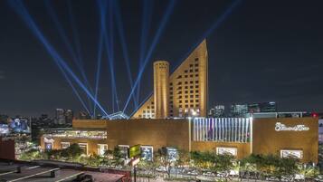 A hotel with a modern design, featuring a prominent tower and a facade with illuminated signage.
