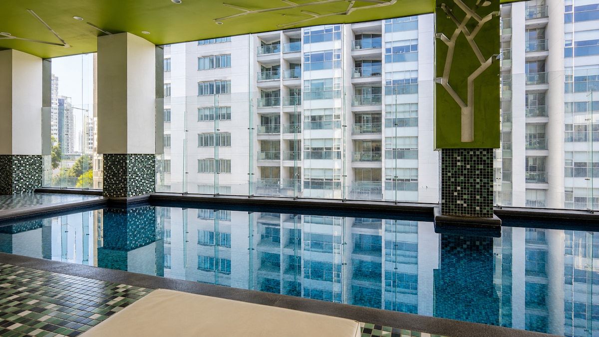 An indoor swimming pool with clear reflections of the surrounding buildings.