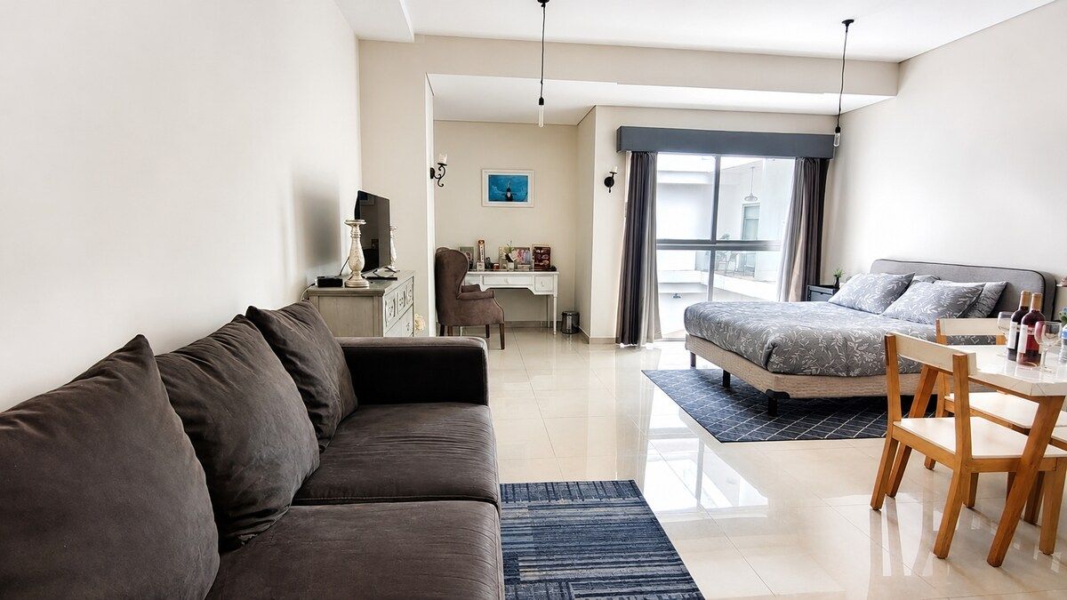 Een moderne hotelkamer met een bank, een bed, een bureau en een eethoek.