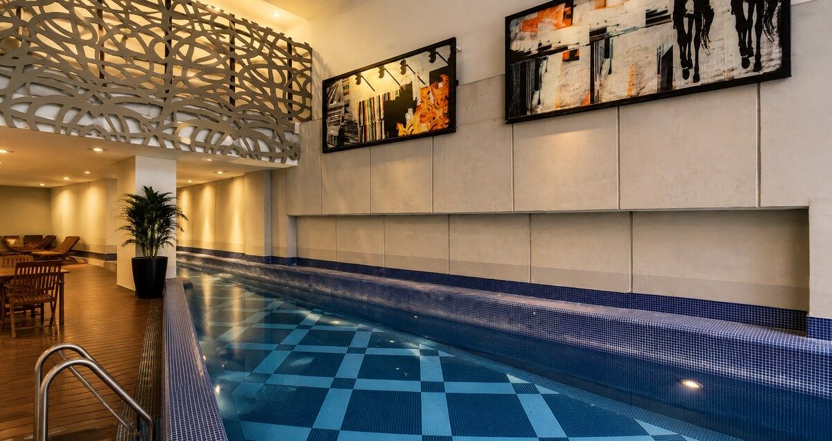 A swimming pool with a checkered floor, lounge chairs, and abstract wall art.