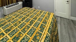 A hotel room with a bed, a television, a door, and a window with curtains. - Moonlight Inn (Gardena)