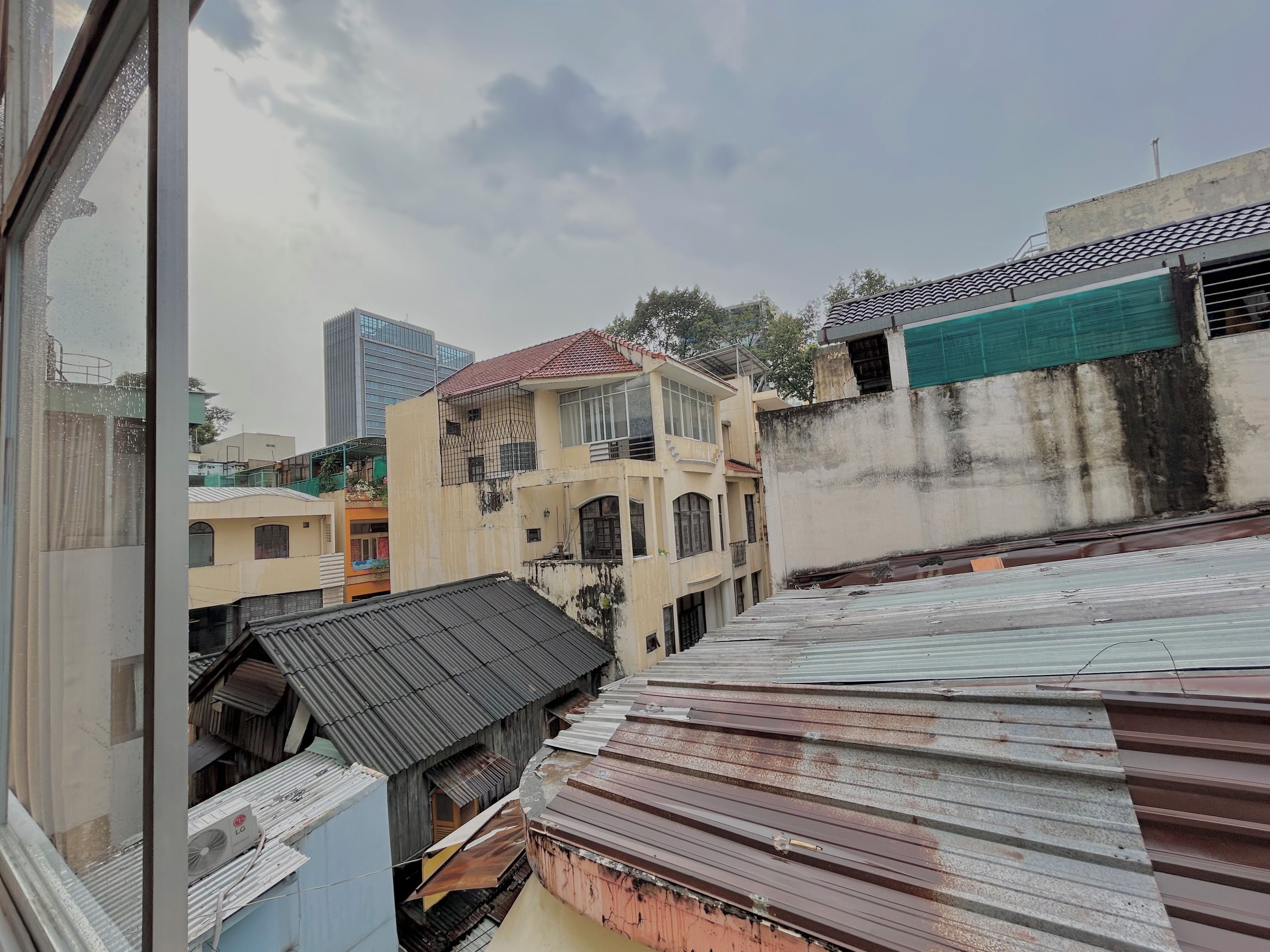 A residential area with buildings of varying architectural styles, including a modern high-rise and older structures with corrugated metal roofs.