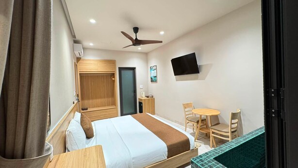 Una habitación de hotel con cama, escritorio, silla, televisor y ventilador de techo.