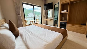 Habitación de hotel con cama, televisión, escritorio y vistas a edificios.