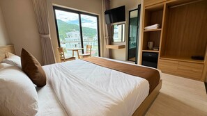 Hotellihuone, jossa on sänky, televisio, työpöytä ja näkymä rakennuksiin.