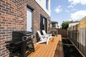 Un patio con barbecue, posti a sedere all'aperto e un pontile in legno.