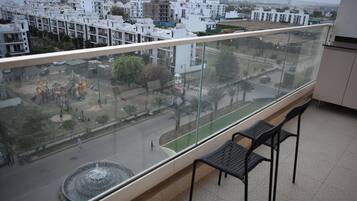 A balcony with a view of a residential area, a playground, and a fountain.