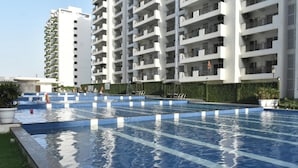 A swimming pool area with multiple lanes, surrounded by high-rise residential buildings. - Flower Valley: Experience Serene Luxury (Sohna)