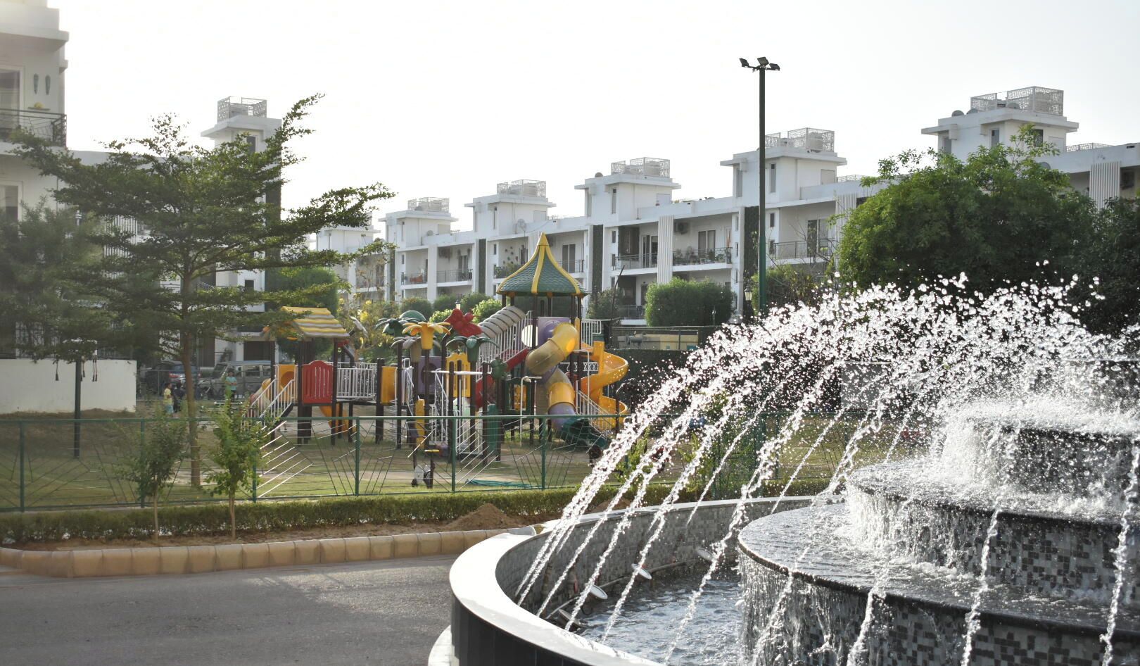 A playground with slides and climbing structures, surrounded by residential buildings.