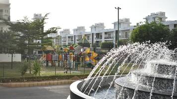 A playground with slides and climbing structures, surrounded by residential buildings.