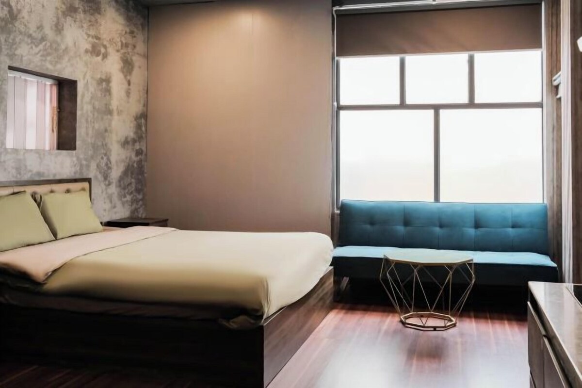 Ein Schlafzimmer mit einem Bett, einem blauen Sofa, einem kleinen Tisch und einem Fenster.