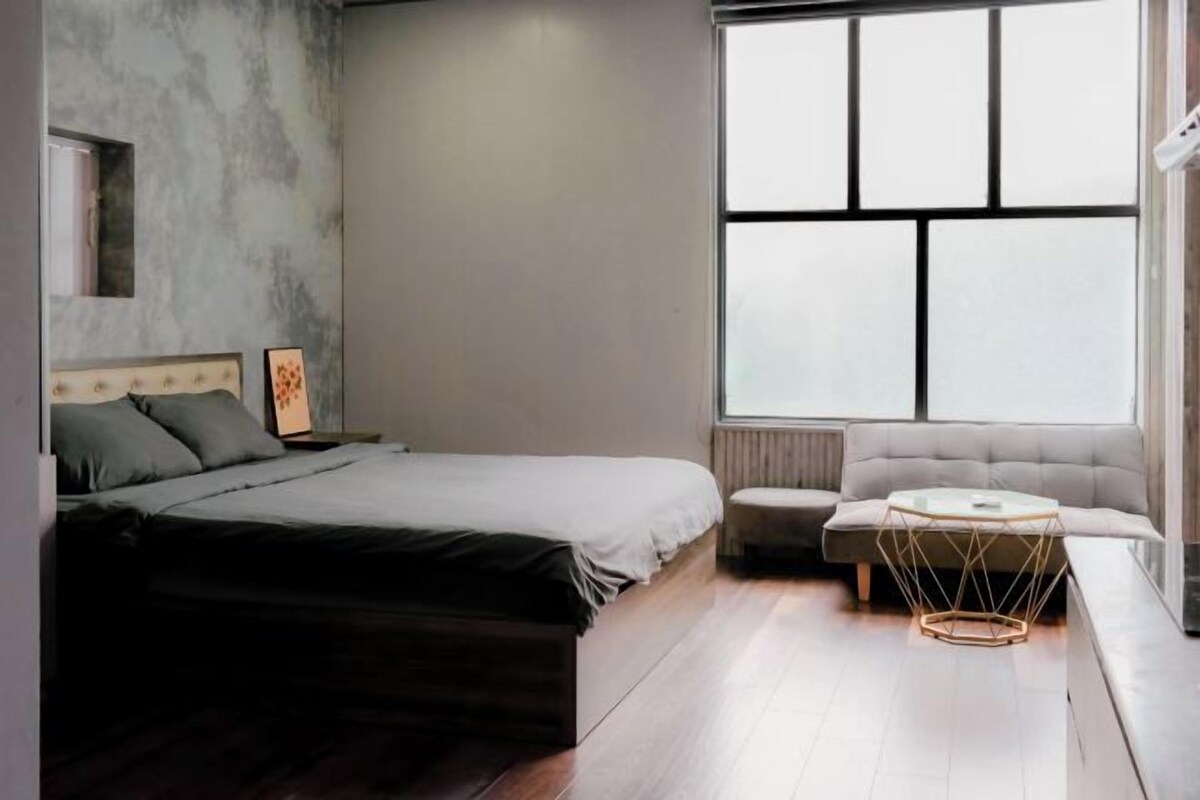 Ein Schlafzimmer mit einem Bett, einem Sofa, einem runden Tisch und einem großen Fenster.