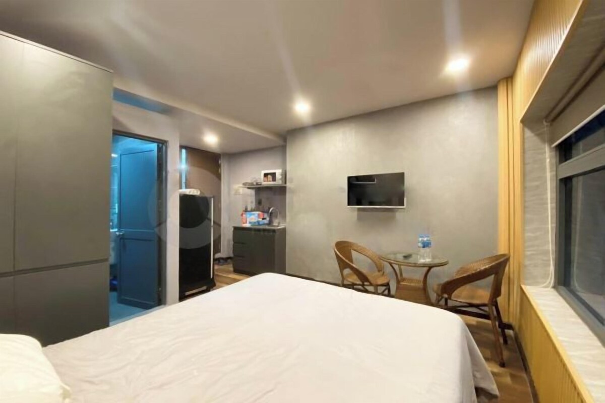 Ein Hotelzimmer mit einem Bett, einem Schreibtisch, einem Sessel, einem Fernseher und einer Küchenzeile.