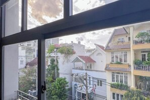 A view through a window with a balcony, overlooking a residential area with multiple buildings and balconies. - Zeus Living - Cozy Apartment in Thao Dien (Ho Chi Minh City)