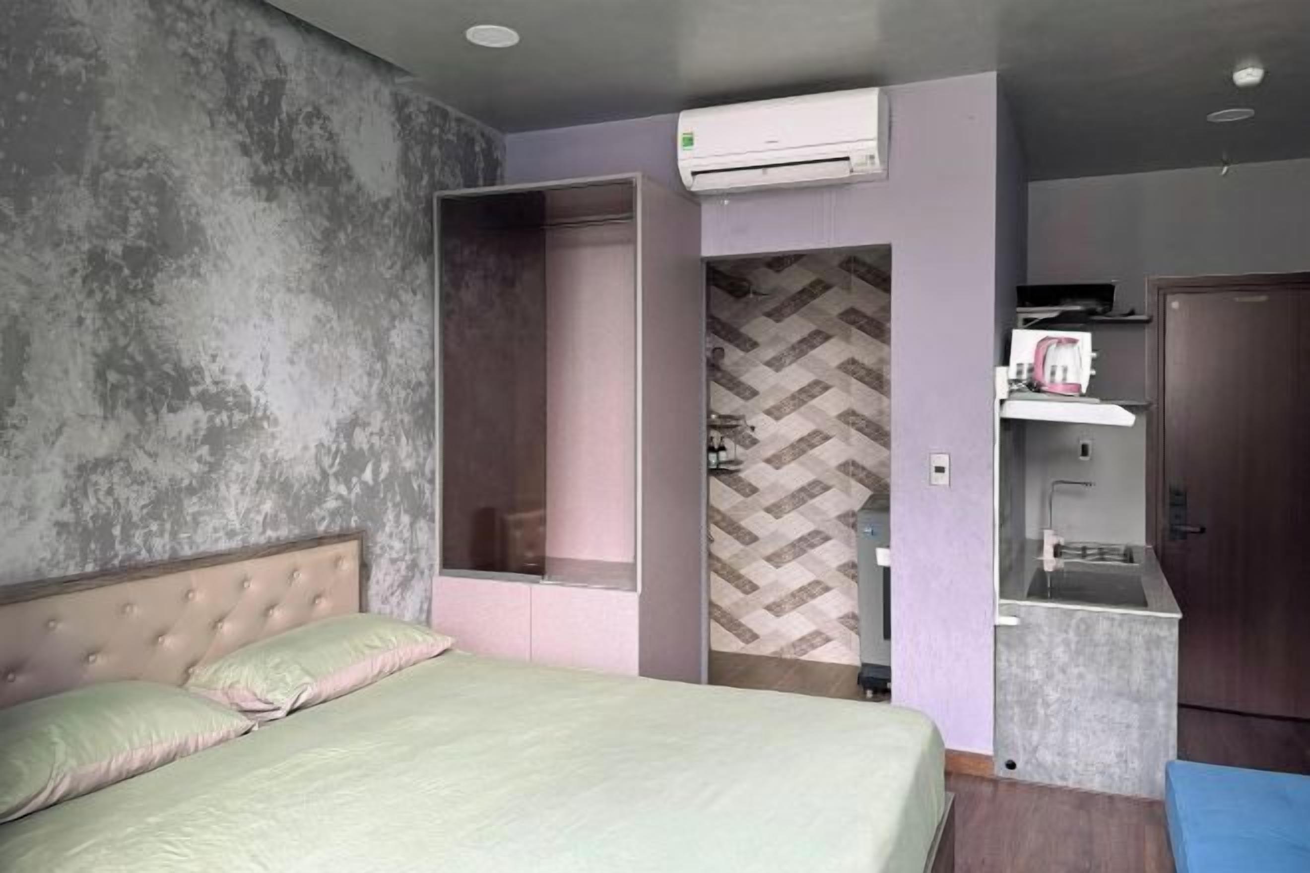 Une chambre d’hôtel équipée d’un lit, d’une armoire, d’une kitchenette et d’un appareil de climatisation.