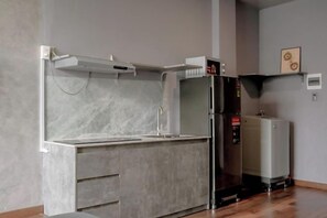 A kitchen with a built-in sink, a refrigerator, and a microwave. - Zeus Living - Cozy Apartment in Thao Dien (Ho Chi Minh City)