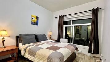 Une chambre à coucher avec un lit, deux lampes de chevet, une fenêtre avec des rideaux et un tableau au mur.