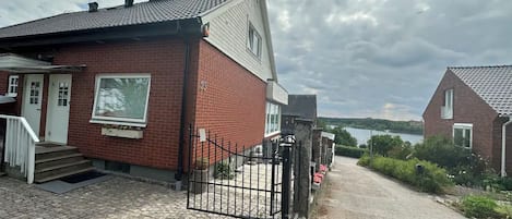 A residential property with a paved driveway, a gated entrance, and a view of a body of water in the background.